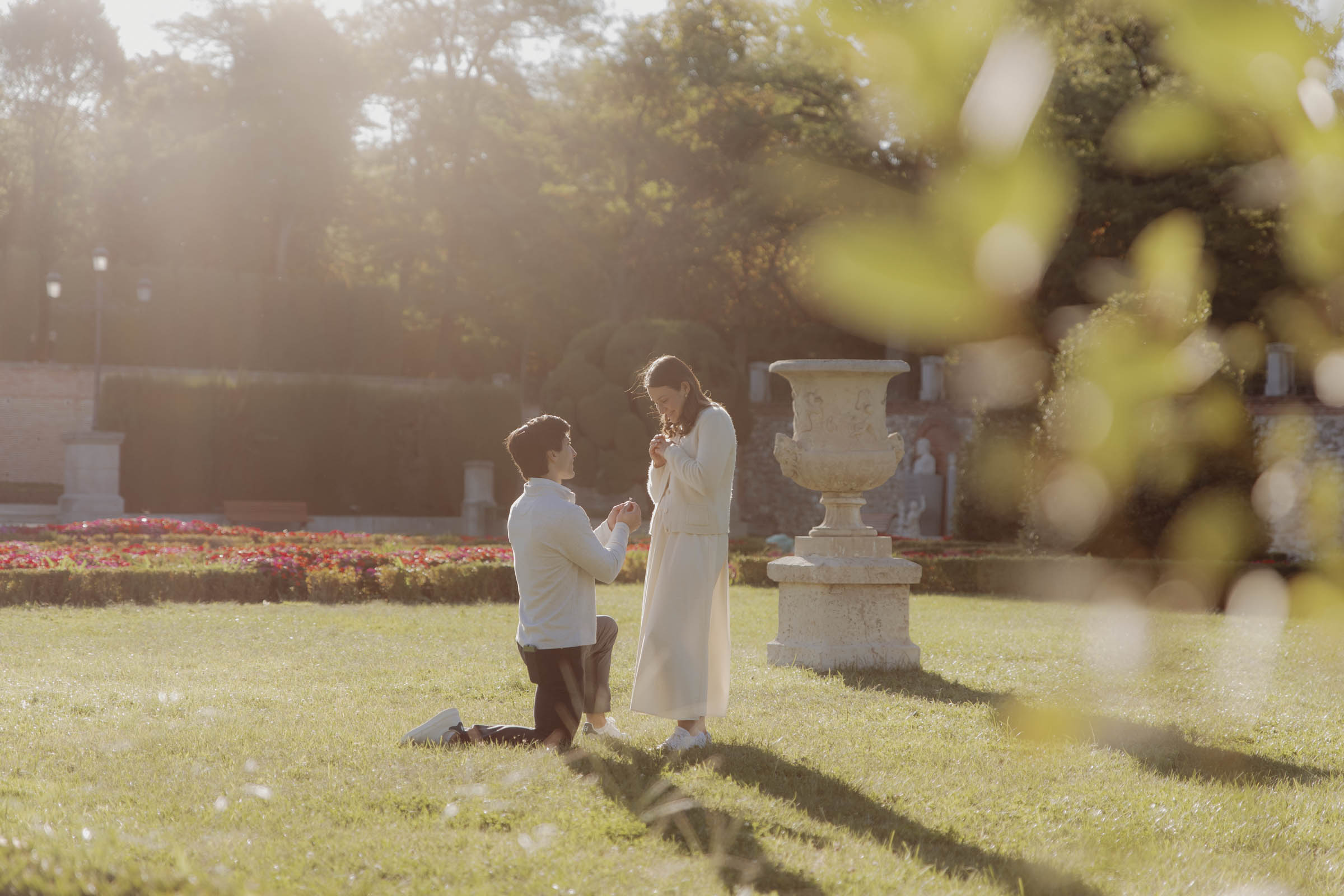 pareja emocionada viviendo su momento de pedida de mano sorpresa en los jardines del parque del retiro al amanecer con fotografa capturando todo