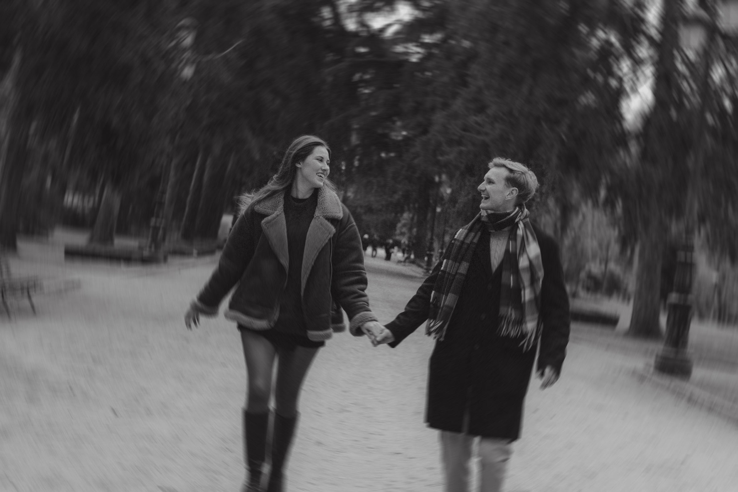 foto de pareja corriendo sonriente y feliz durante su sesion de compromiso en los jardines del campo del moro de madrid